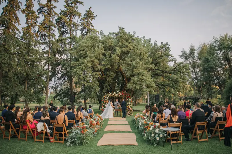 Ceremonia en el parque con los invitados sentados frente al arco