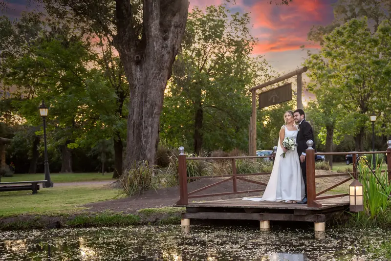 Novios en el puente rojo sobre el lago al atardecer