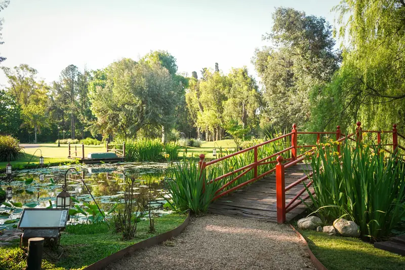 El jardín del predio con el puente rojo sobre el lago