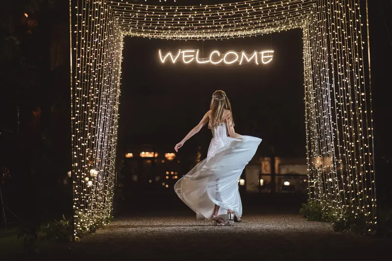 Quinceañera bailando bajo un arco de luces que dice Welcome